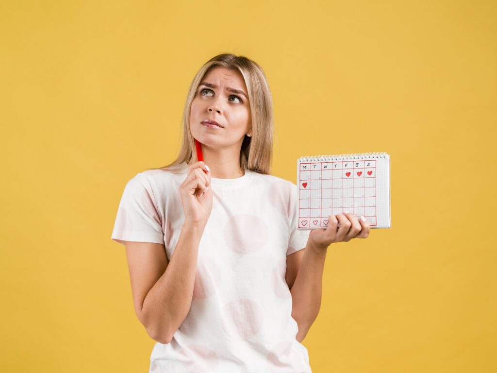 mulher segurando calendário que representa o ciclo menstrual