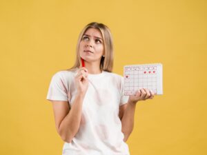 mulher segurando calendário que representa o ciclo menstrual